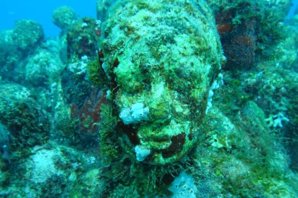 Coral-covered statue at the MUSA Underwater Museum in Cancún, Mexico