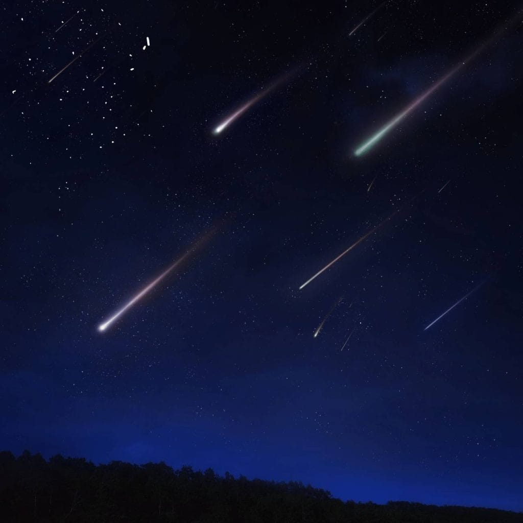 Unexplained Events 2026: meteor shower streaking across a dark navy night sky with glowing trails above a silhouetted treeline