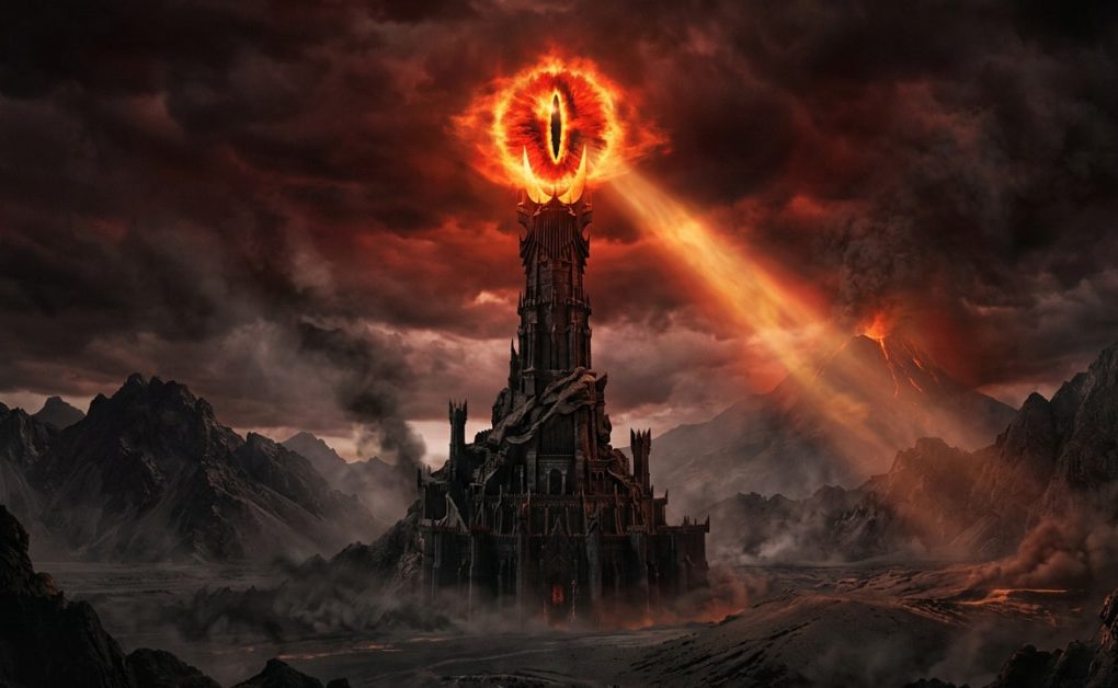 Flaming supernatural Eye of Sauron atop the dark fortress of Barad-dûr, casting a glowing beam of light over the volcanic ash landscape of Mordor.