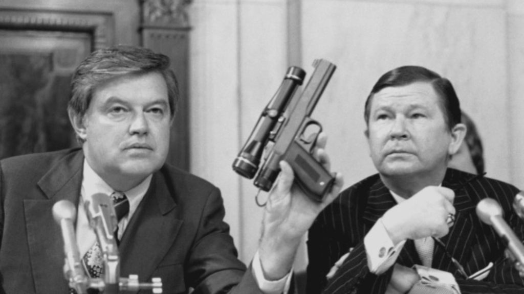 Frank Church holds a CIA poison dart gun during a 1975 Church Committee hearing