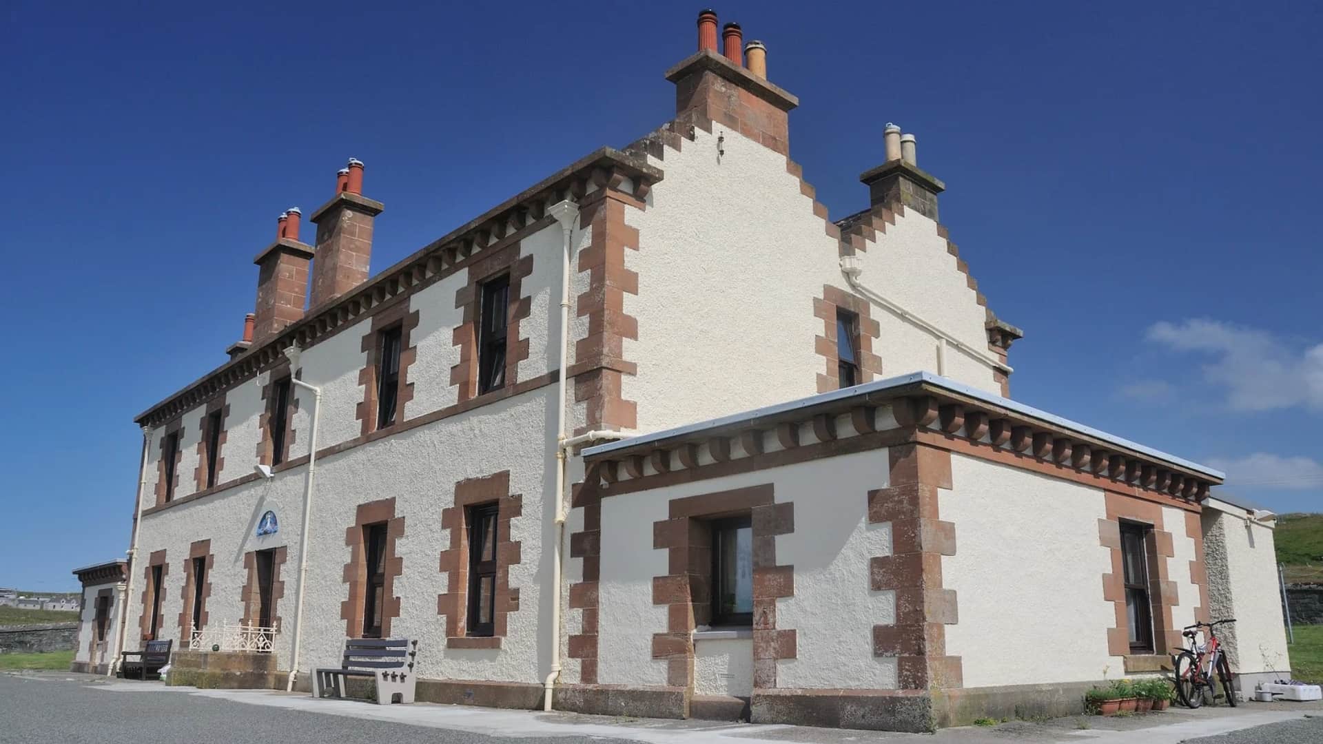 Former Flannan Isles lighthouse keepers’ shore station at Breasclete, with white walls, red sandstone trim and stepped gables.